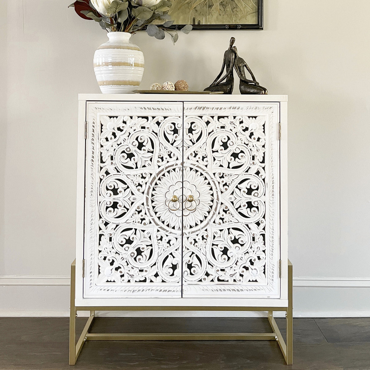 This white wooden cabinet has ornate details and a gold base.